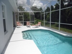 A swimming pool with a glass enclosure, surrounded by white walls and a few lounge chairs. - Relaxing Vacation Home w/ Lake,Golf,Pool,Tennis,Internet,Cable,Sunsets (Davenport)