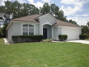 A single-story house with a front entrance, a garage, and a well-maintained lawn. - Relaxing Vacation Home w/ Lake,Golf,Pool,Tennis,Internet,Cable,Sunsets (Davenport)