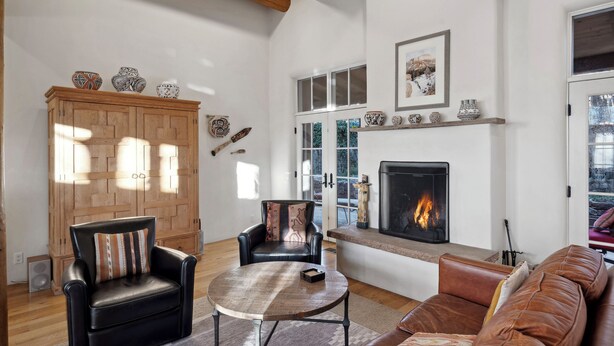 Una sala de estar acogedora con chimenea, muebles de cuero y vigas de madera en el techo.