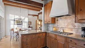 Una cocina con gabinetes de madera, una isla grande e intenso revestimiento de azulejos.