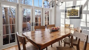 Un comedor con una mesa de madera, sillas y una araña.