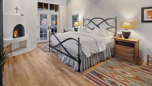 Un dormitorio con cama, chimenea, mesita de noche y suelo de madera.