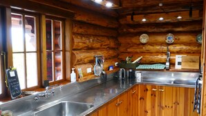A kitchen with wooden cabinets, stainless steel countertops, a dishwasher, and a sink.