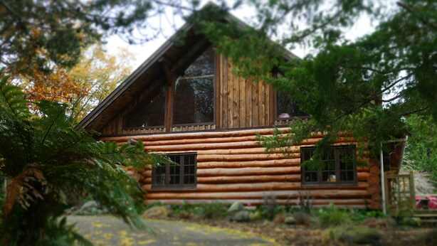 A log cabin with a large window and a porch.