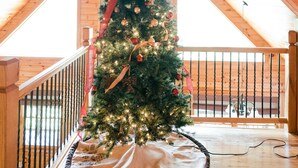 Een kerstboom in een houten interieur met een stenen muur en een houten balustrade.