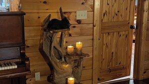 Un interior de madera con un piano, una estructura de madera tallada con velas, y una puerta de madera.