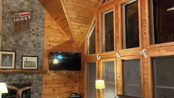 Ein Holzinterieur mit Kamin aus Stein, einer Ledersofa und einem Deckenventilator.