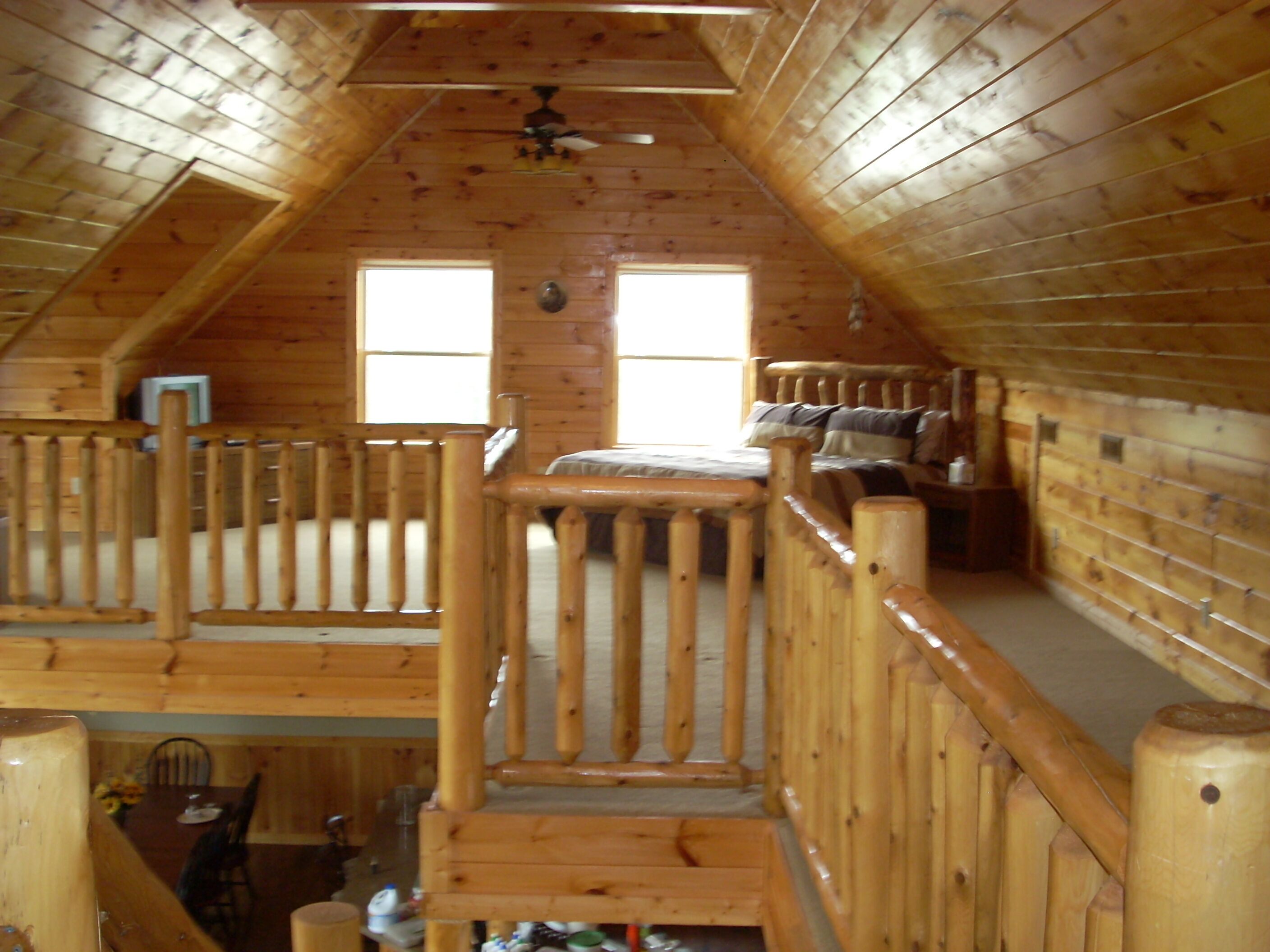 Een houten chalet met een slaapkamer op de zolder, een eethoek en een keuken.