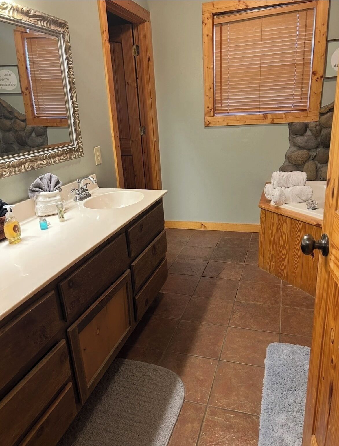 Un baño con tocador de madera, un espejo grande, un lavamanos y una bañera con toallas.