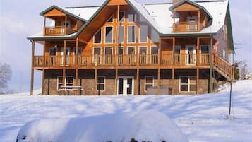 Ein großes, mehrgeschossiges Holzhaus mit Steinunterbau, mehreren Balkonen und einer großen amerikanischen Flagge.