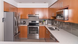 A modern kitchen with stainless steel appliances, wooden cabinets, and a tiled backsplash. - CEDAR RIDGE 17 | Prime Ski-In, Ski-Out Location | Private Garage & Hot Tub (Whistler)