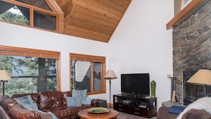 A cozy living room with leather sofas, a wooden coffee table, and a stone fireplace. - CEDAR RIDGE 17 | Prime Ski-In, Ski-Out Location | Private Garage & Hot Tub (Whistler)