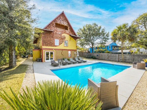 Ein Haus mit Swimmingpool, umzäunter Garten und einer Holzterrasse.