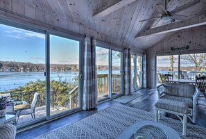 Eine geräumige Veranda mit großen Fenstern, die Blick auf einen See und die umliegende Landschaft bietet.
