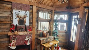 Ein gemütliches Blockhauszimmer mit Kamin, Weihnachtsbaum und rustikalen Holzwänden.