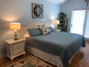 A bedroom with a bed, nightstands, a dresser, a decorative wall piece, and a window with blinds. - 5 min to Gulf beach. On bike path. Pvt htd pool. Boat parking. Great kitchen.  (Eastpoint)