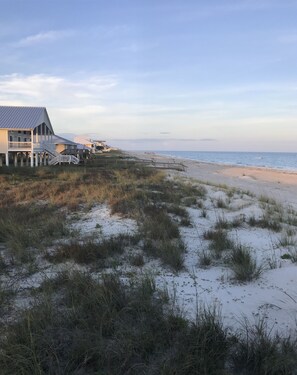 A beachfront property with a series of buildings featuring balconies and a wooden walkway leading to the beach.