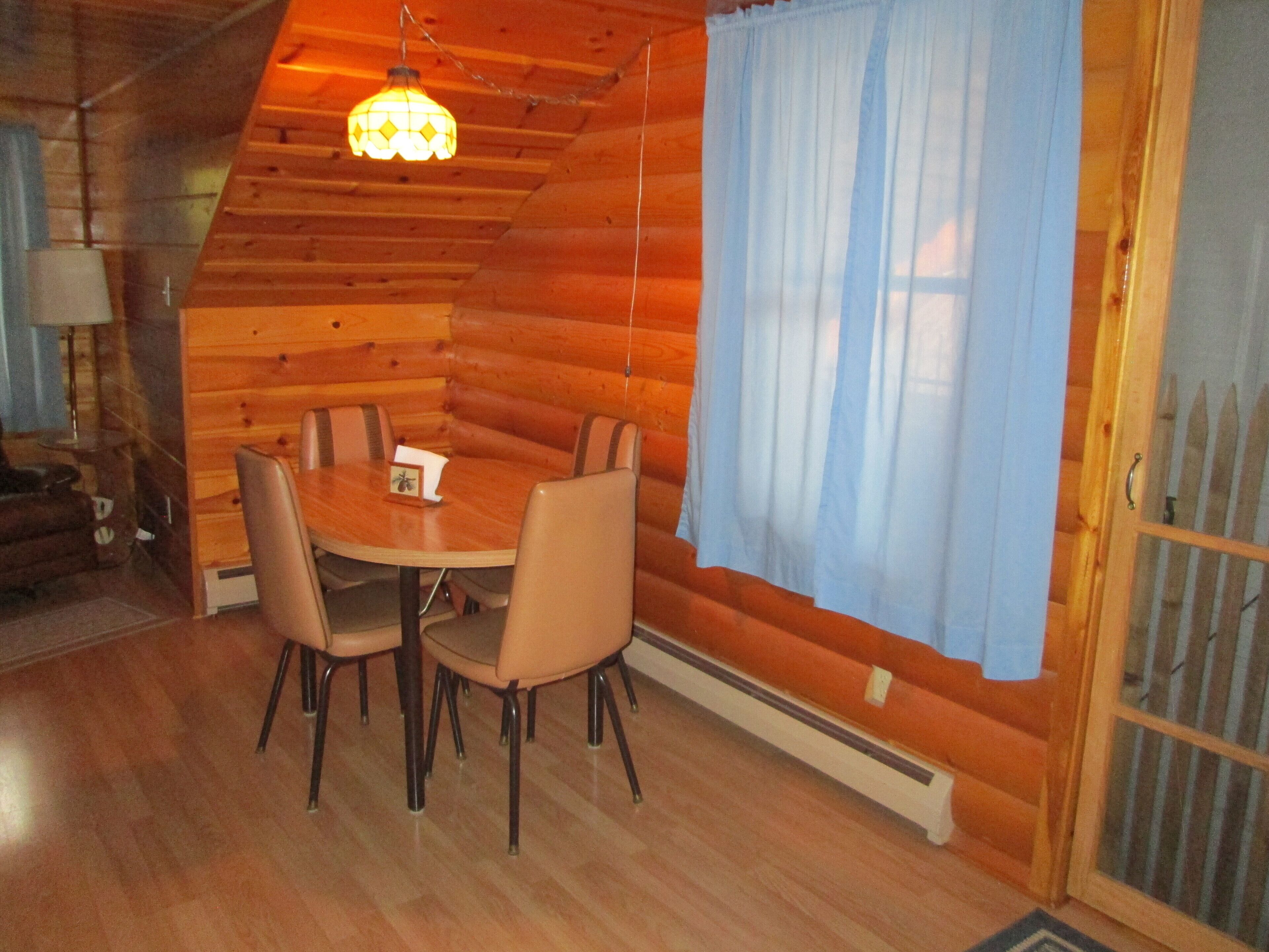 A cozy wooden cabin with a dining area featuring a round table and four chairs.