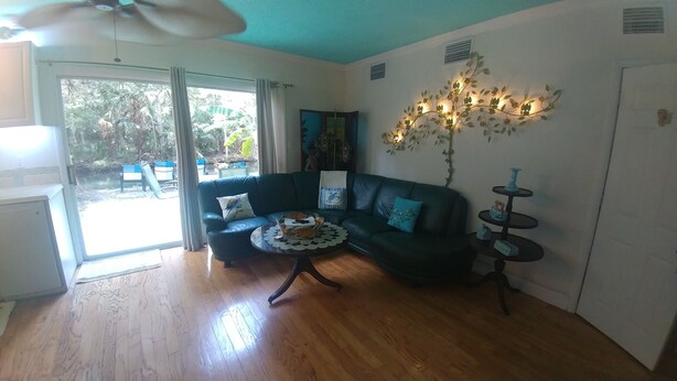 Ein Wohnzimmer mit einem dunkelgrünen Sofa, einem Couchtisch und einem Wandbild.