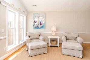 A room with two armchairs, a side table with a lamp, and a painting on the wall.