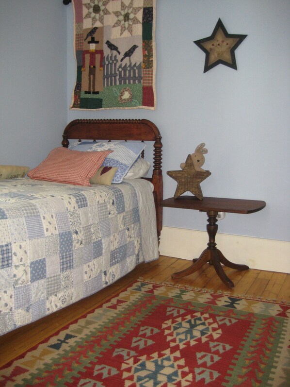 Une chambre à coucher avec un lit en bois, une courtepointe, une décoration murale en forme d’étoile et une petite table sur laquelle se trouve un objet en forme d’étoile.