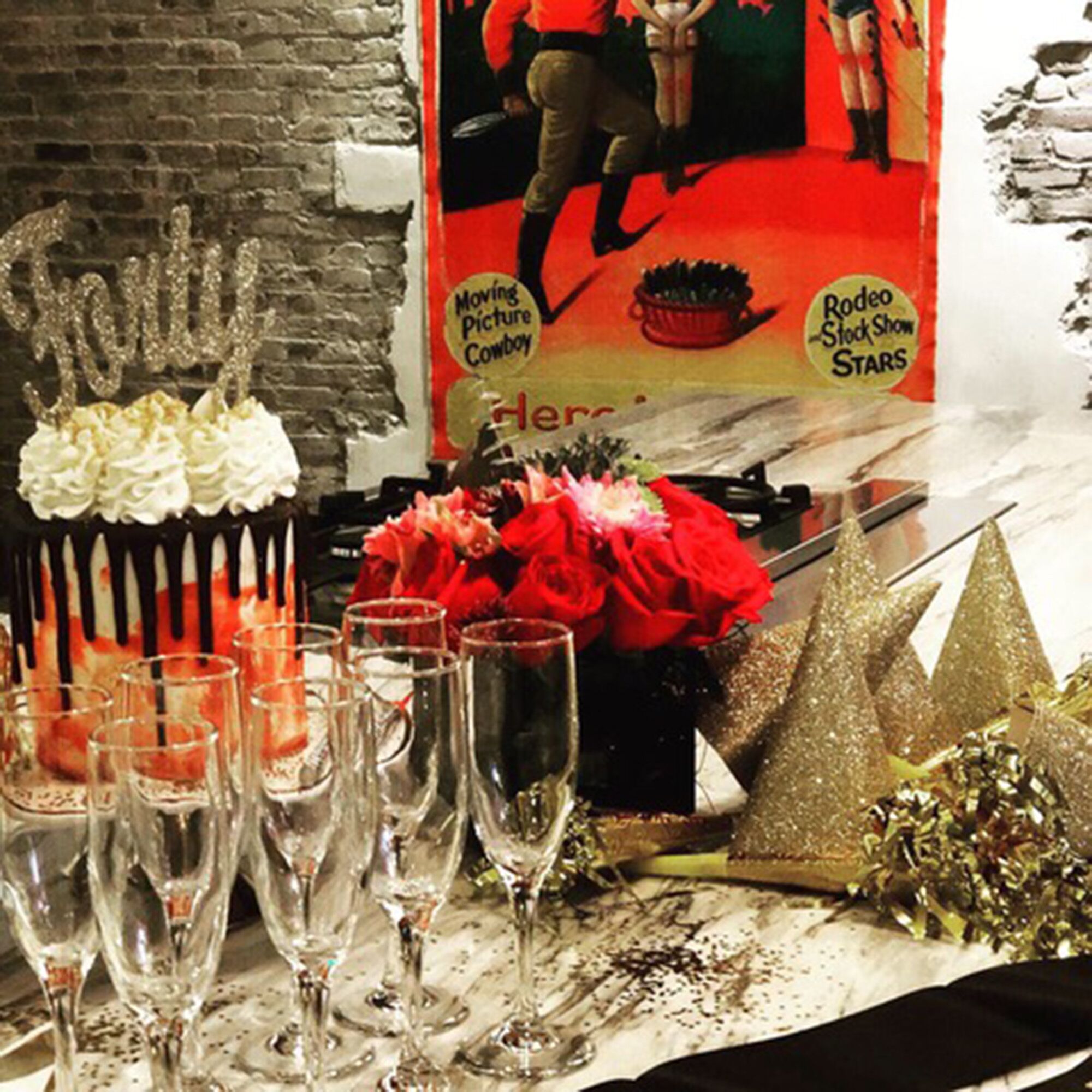 Une table avec un gâteau, des roses rouges et des coupes à champagne.