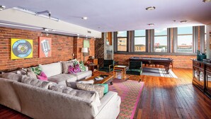 Uma sala de estar moderna com parede de tijolos, mesa de bilhar e grandes janelas com vista para a cidade.