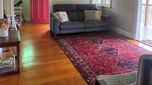Ein Wohnzimmer mit einem blauen Sofa, einer roten Tür, einem großen Teppich und einem weißen Sessel.