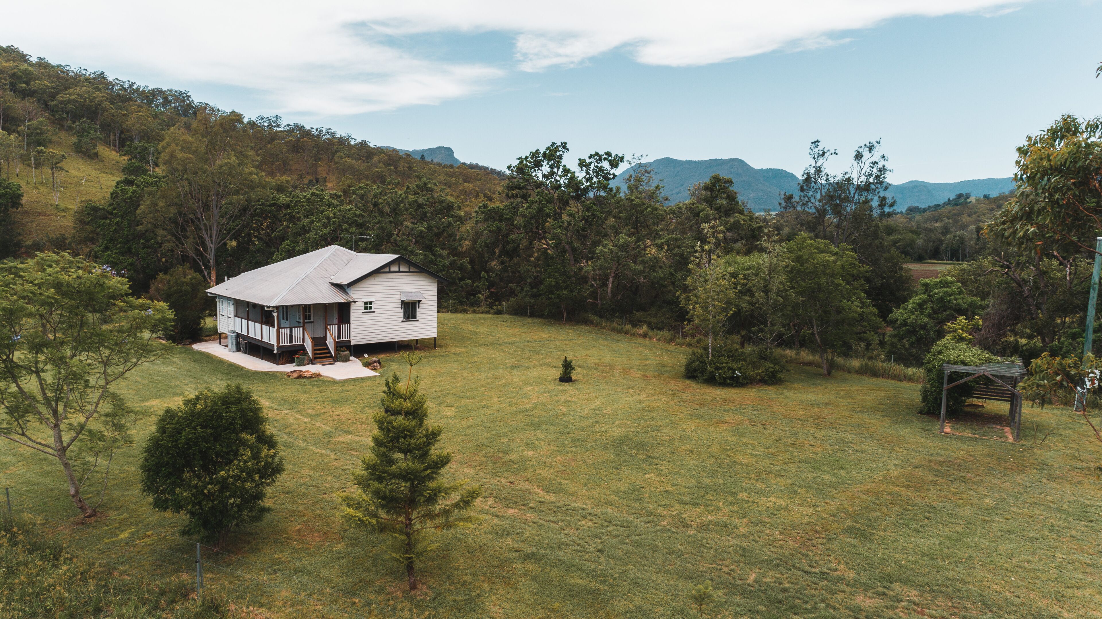 A house with a porch, surrounded by a grassy yard and trees.