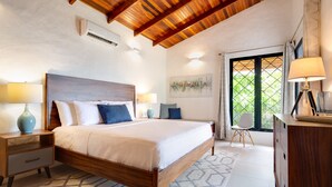 A bedroom with a wooden ceiling, a bed with white bedding, a nightstand with a lamp, a dresser, and a window with curtains. - AMAZING Hillside Home, Private Infinity Pool, Covered Veranda, Spacious Rooms (Manuel Antonio)