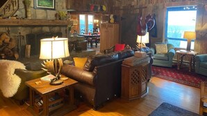 Un salon chaleureux avec une cheminée, un canapé en cuir et, au fond, un coin repas.