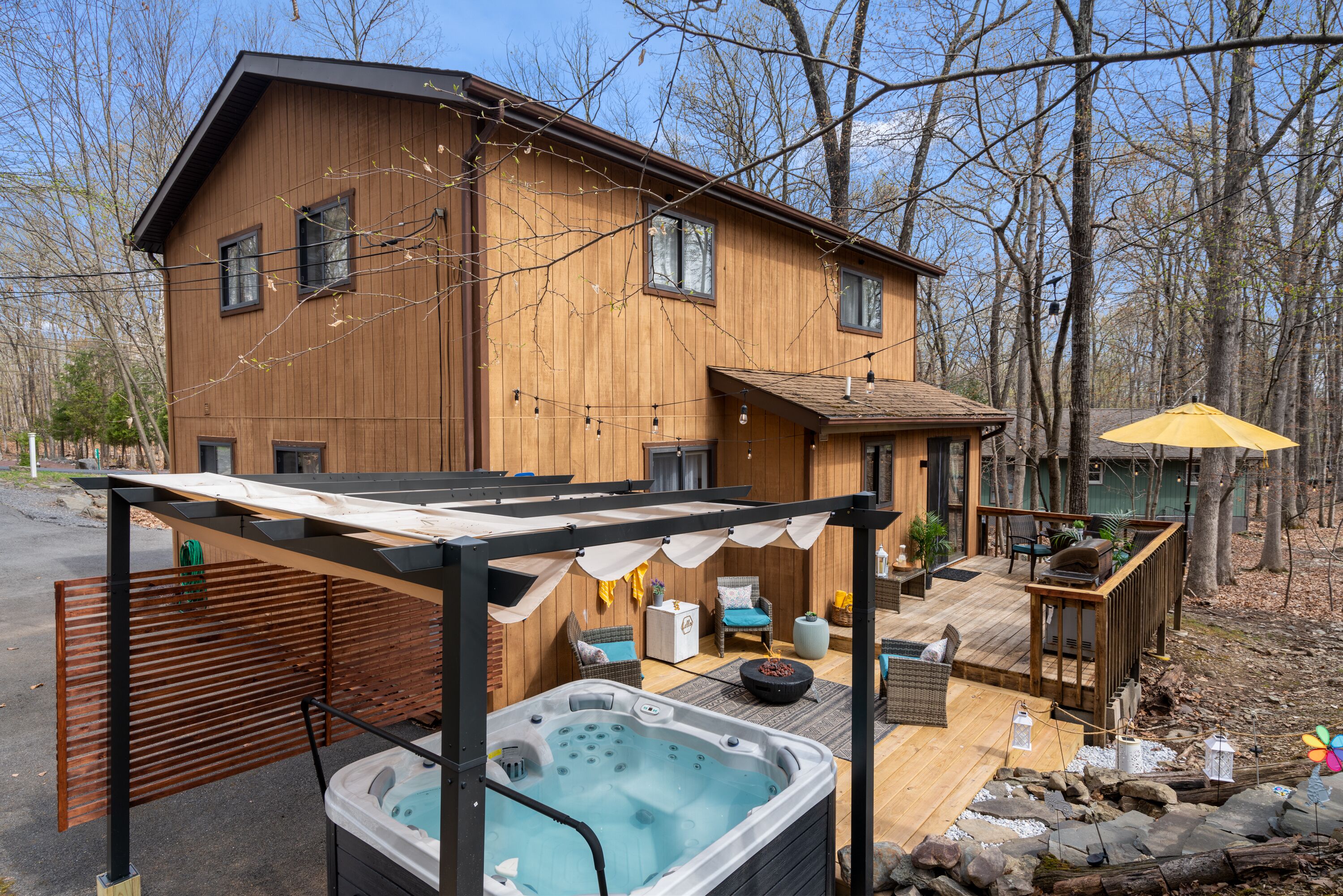 Une maison en bois dotée d’un bain à remous, d’un espace salon extérieur et d’une terrasse.