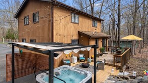 A wooden house with a hot tub, outdoor seating, and a deck.