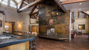 Un intérieur spacieux agrémenté d’une cheminée en pierre, de poutres en bois et d’un coin bar.