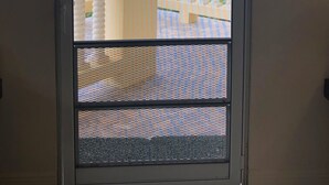 A door with a view of a balcony and lush greenery.