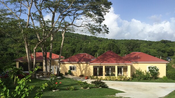 A two-story house with a red roof, surrounded by a well-maintained lawn and trees.