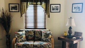 A living room with a floral sofa, a wooden coffee table, and a side table with a lamp.