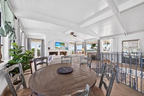 A spacious living area with a round wooden table, comfortable seating, and a view of the outdoors.