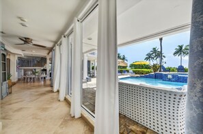 A spacious indoor area with a view of a pool and palm trees outside.