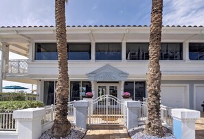 A two-story building with a balcony, a gated entrance, and a decorative pediment.