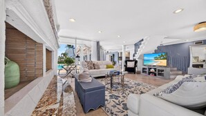 Un salón amplio con televisor grande, asientos cómodos y vistas al exterior.