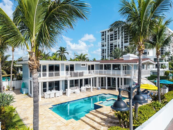 A resort with a pool, outdoor seating, and palm trees.