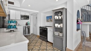 Una cocina moderna con armarios blancos, electrodomésticos de acero inoxidable y piso de baldosas con diseño.