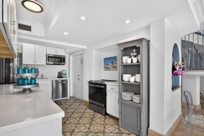 Una cucina moderna con mobili bianchi, elettrodomestici in acciaio inossidabile e un pavimento in piastrelle decorate.