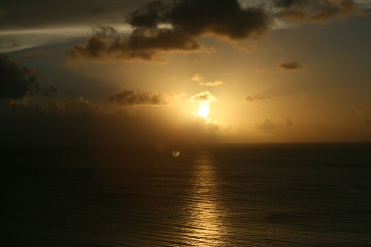 A sunset over a calm sea with clouds in the sky.