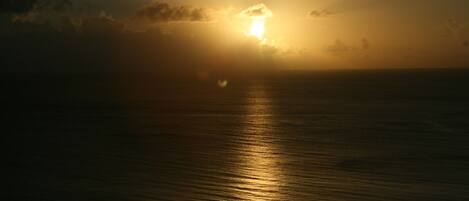 A sunset over a calm sea with clouds in the sky.