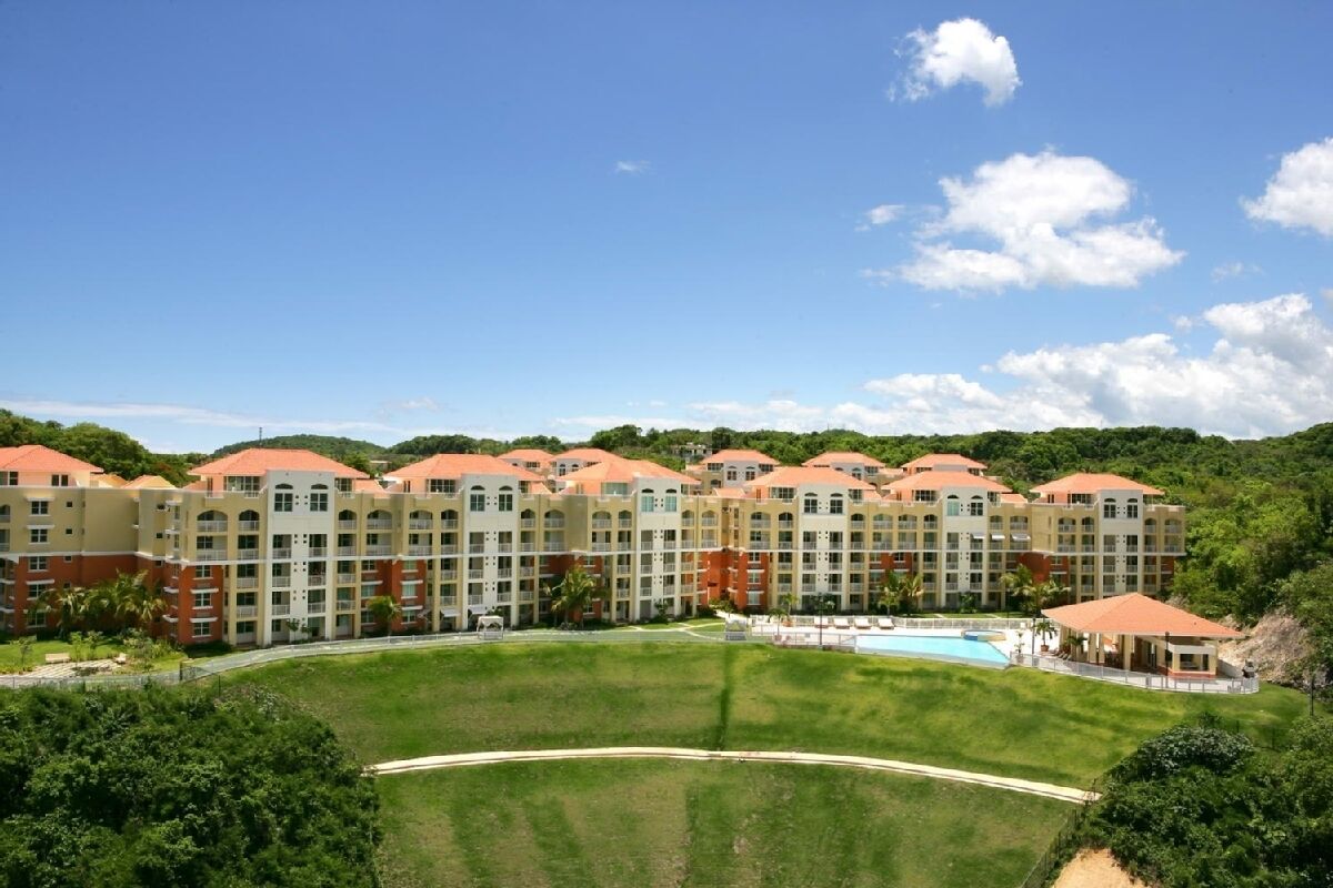 Un hotel con varias edificaciones, piscina y césped bien cuidado.