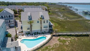 A multi-story building with a swimming pool, a beach, and a pier. - 113 Waters Edge - Sunset Haven - Renovated Riverside Townhome - Pool & Fishing Pier (Folly Beach)