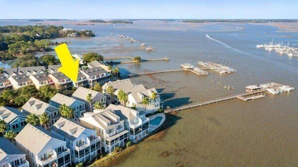 A coastal residential area with houses along the water's edge, a marina with boats, and a clear view of the water. - 113 Waters Edge - Sunset Haven - Renovated Riverside Townhome - Pool & Fishing Pier (Folly Beach)
