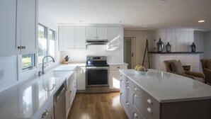 Ett modernt kök med vita skåp, rostfria vitvaror och en stor köksö.